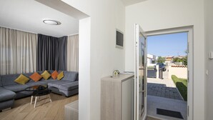 Una sala de estar moderna con un sofá gris, una mesa de centro y una puerta que da a un balcón.