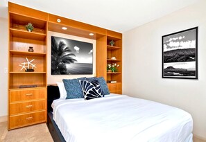 Ein Schlafzimmer mit einem Bett, Holzregalen mit Dekoration und zwei gerahmten Bildern an der Wand.