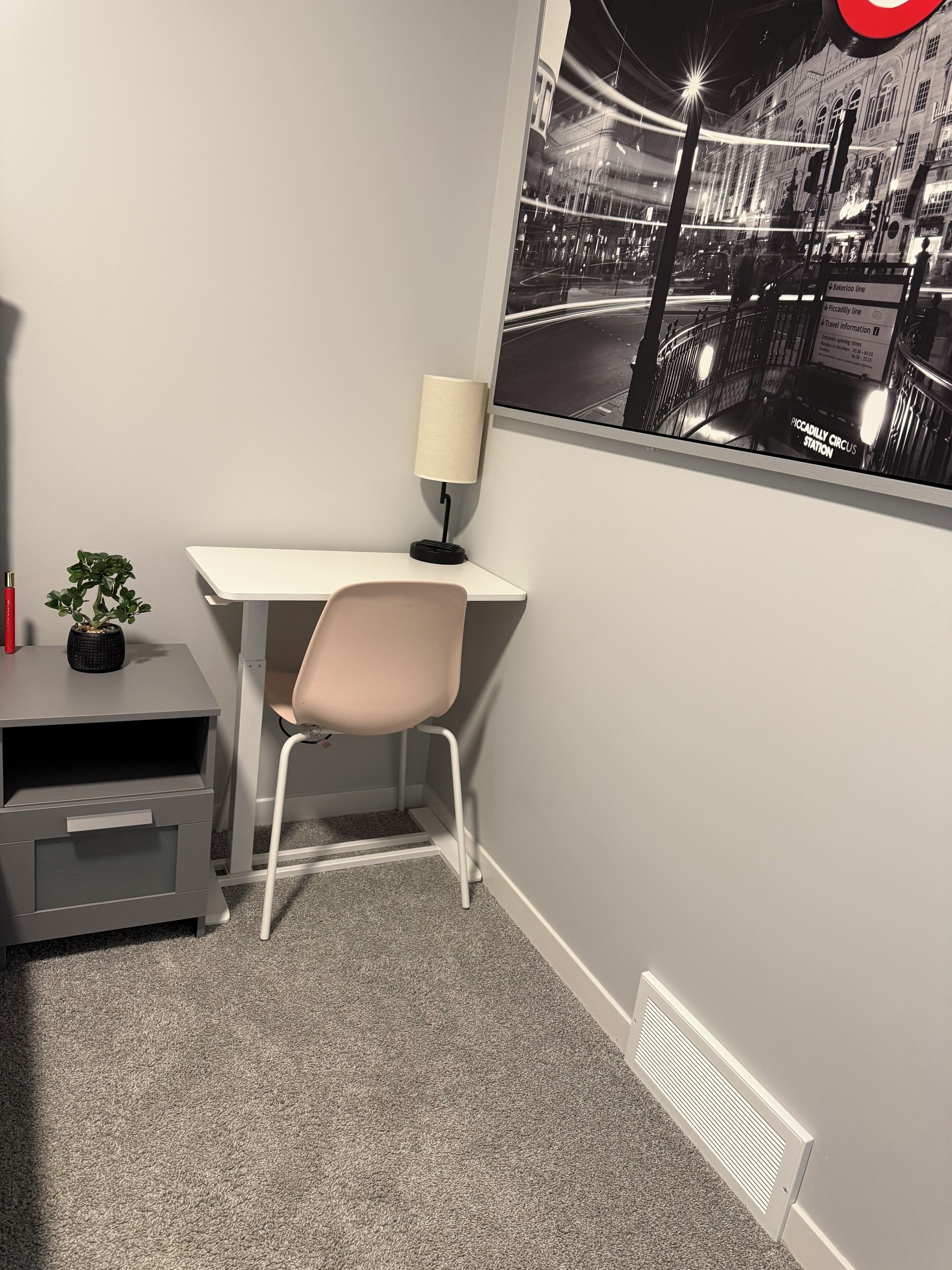 A modern office space with a desk, chair, lamp, and a view of a city street at night.