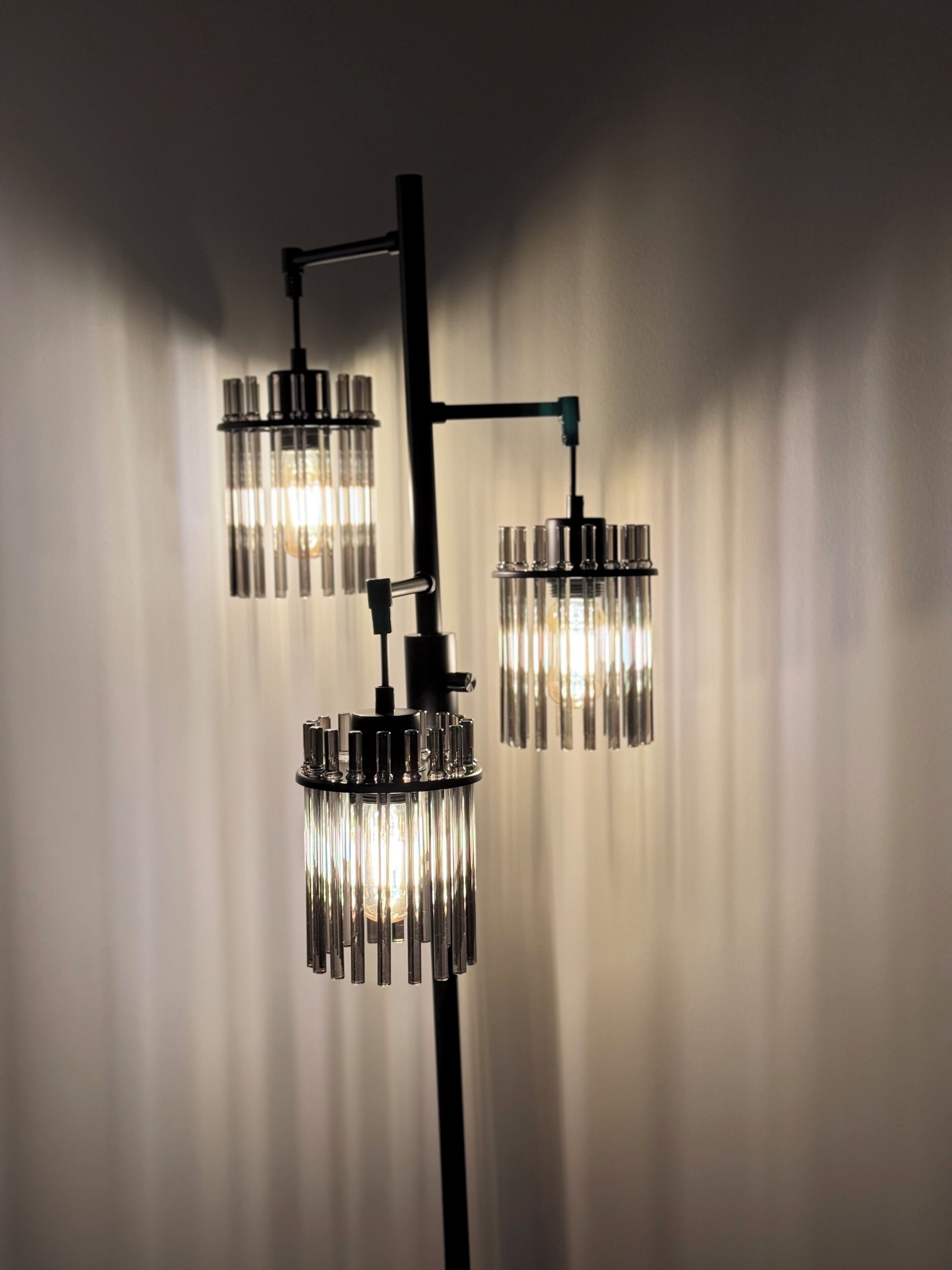 A modern chandelier with three cylindrical glass shades and a central metal structure.