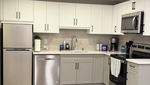 Una cocina moderna con armarios blancos, electrodomésticos de acero inoxidable y salpicadero de azulejos.