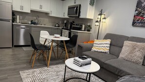 Una cocina moderna con armarios blancos, un microondas y un comedor con mesa y sillas.