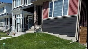 Un edificio residencial con un césped cuidado, un porche delantero y una escalera que conduce a la entrada.