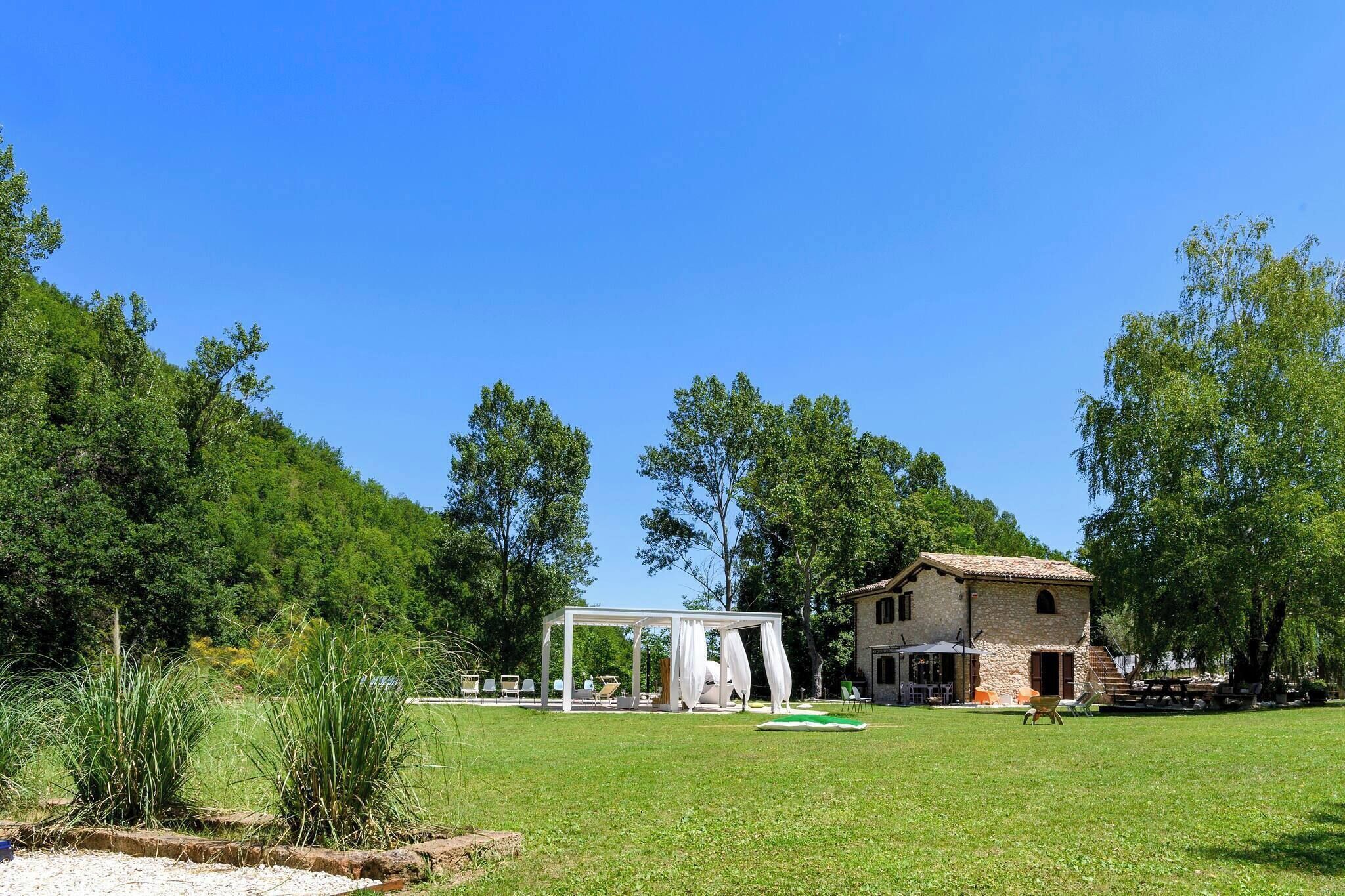 Ein rustikales Steinhaus mit Garten, Laube und blauem Himmel.