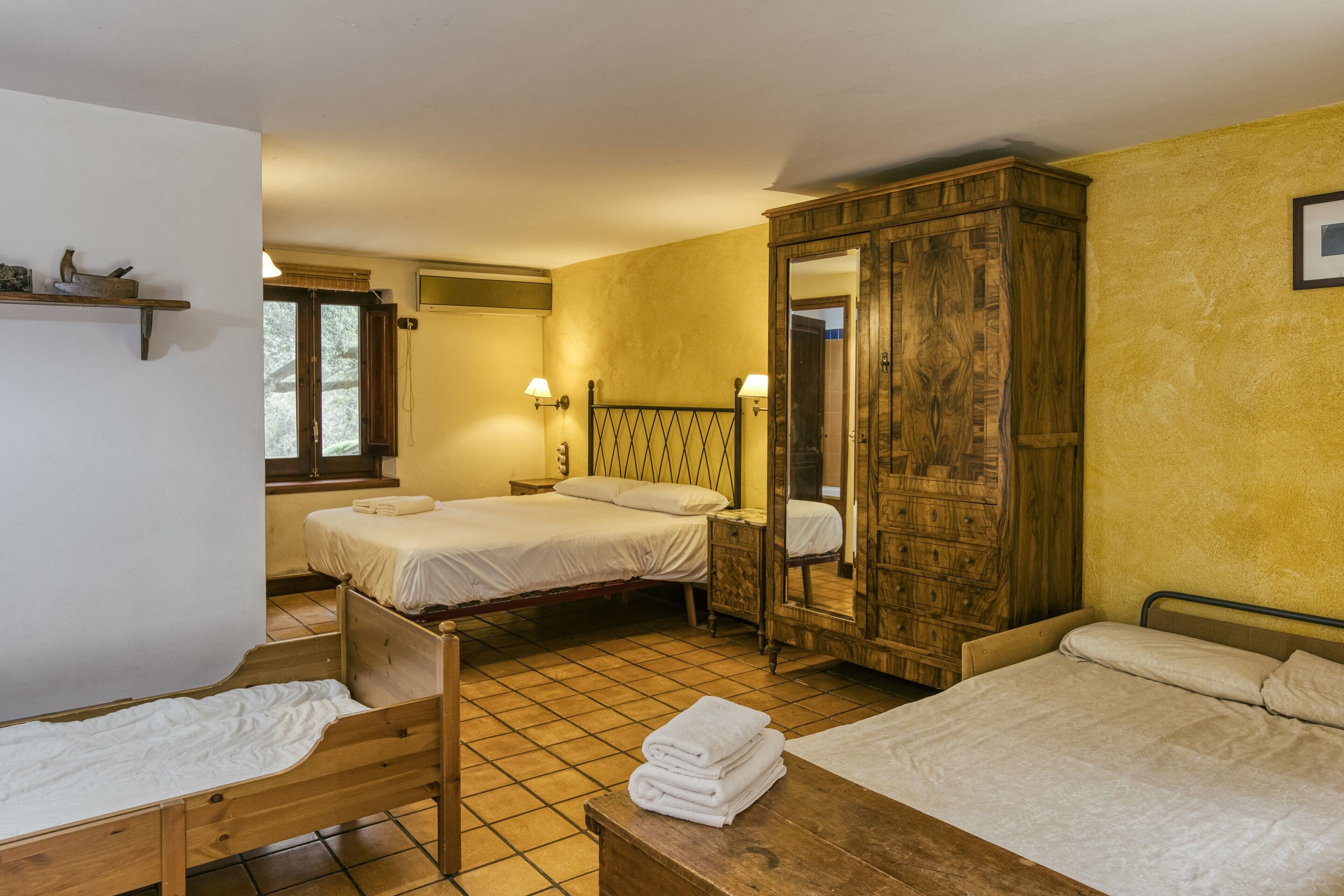 Een kamer met twee bedden, een houten garderobe, een spiegel en een klein tafeltje met handdoeken.