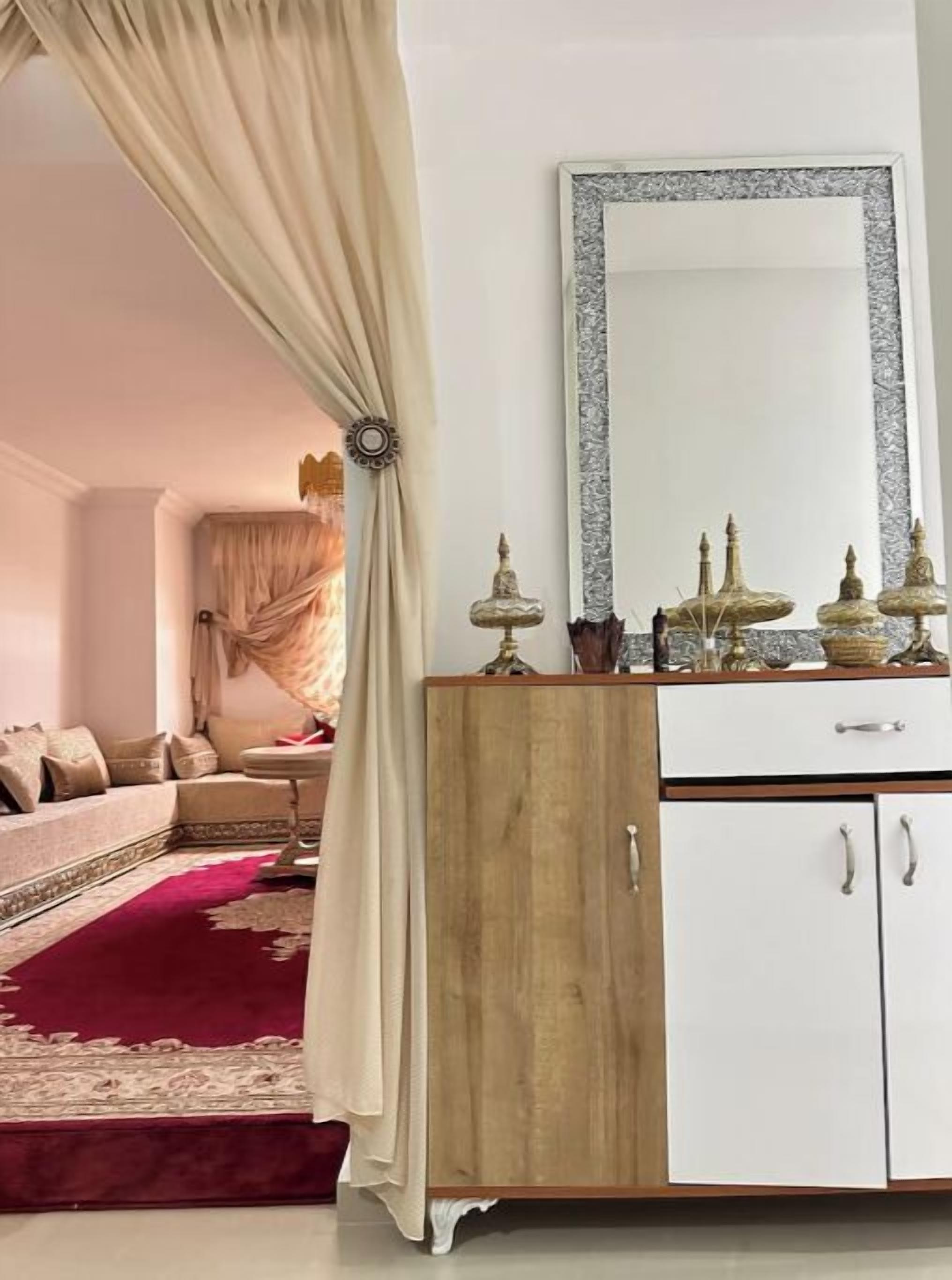 Una habitación con sofá, un armario de madera y un espejo.