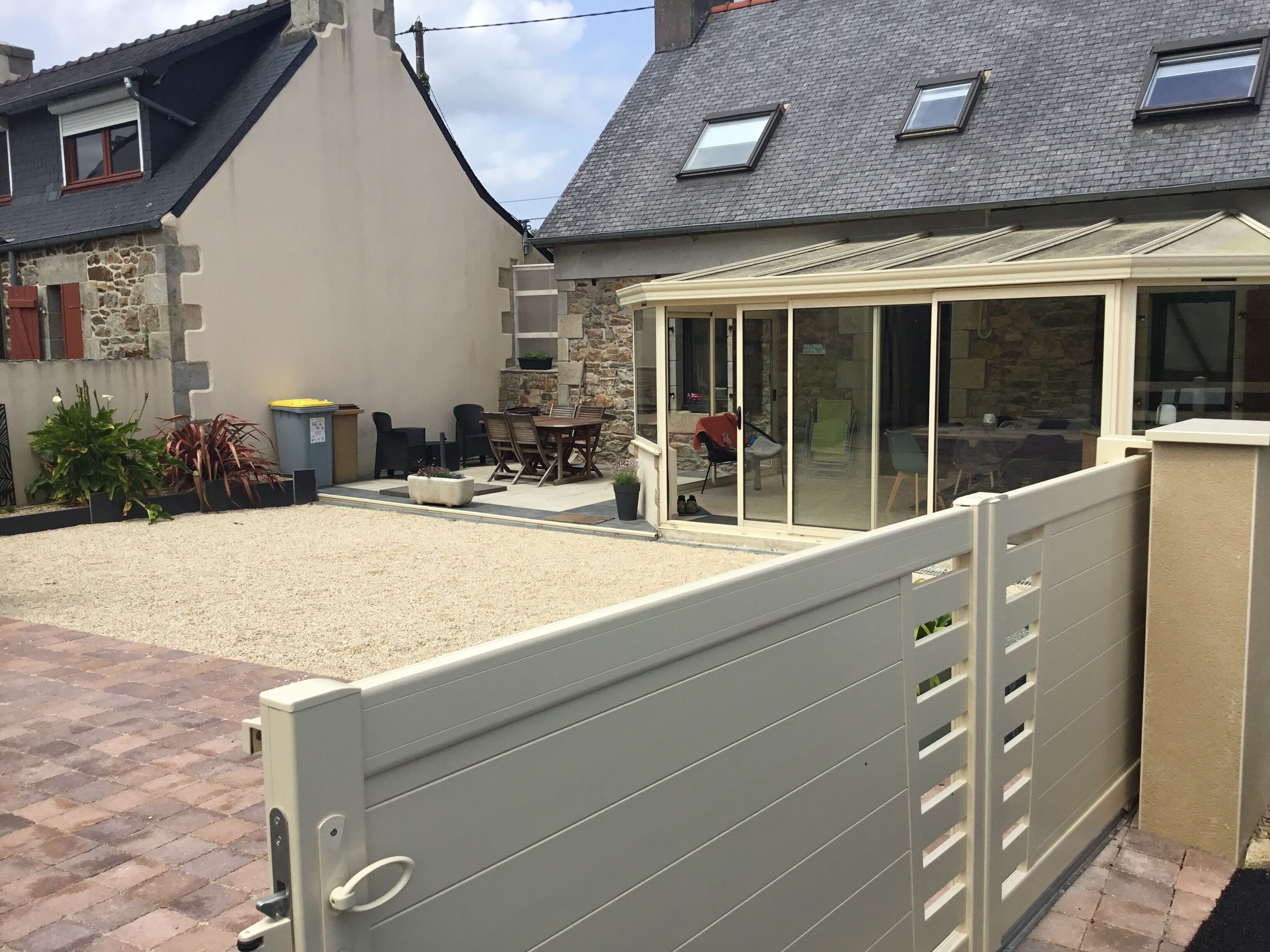 A gated outdoor area with a patio, stone walls, and a conservatory.