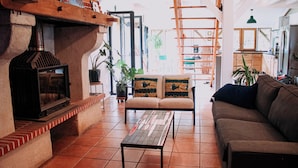 A cozy living room with a fireplace, a sofa, a coffee table, and a bookshelf.