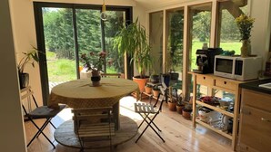 A kitchen with a round table, chairs, potted plants, and a microwave on a shelf.