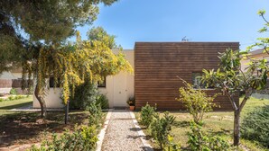 Un bâtiment moderne doté d’une façade en bois, d’un chemin de gravier et de divers petits arbres et arbustes.