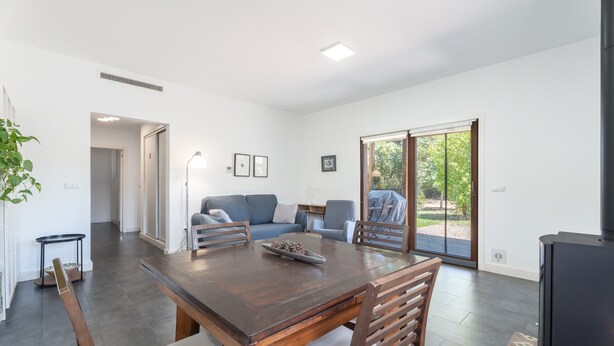 Un salon moderne comprenant une table à manger, un canapé et une grande porte-fenêtre coulissante donnant sur un espace extérieur.