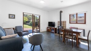 Un grand salon comprenant un canapé, des fauteuils, une table à manger et un téléviseur.