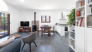 Un salon moderne comprenant un canapé, un téléviseur, une table à manger et des chaises. Il y a également un coin cuisine avec une cuisinière, un évier et une bibliothèque.
