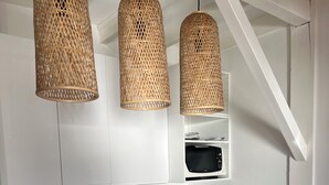 A modern kitchen with white cabinetry, a stainless steel sink, and a wooden island. There are three woven pendant lights hanging above the island. - QUIET PIED A MER WITH EXCEPTIONAL VIEWS AND CLOSE TO RESORT CENTER (Saint-Palais-sur-Mer)