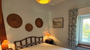 A bedroom with a large bed, a bedside table with a lamp, a wall-mounted shelf, and a window with curtains. - QUIET PIED A MER WITH EXCEPTIONAL VIEWS AND CLOSE TO RESORT CENTER (Saint-Palais-sur-Mer)