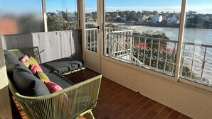 A balcony with a wicker sofa, a view of a river, and a distant town. - QUIET PIED A MER WITH EXCEPTIONAL VIEWS AND CLOSE TO RESORT CENTER (Saint-Palais-sur-Mer)