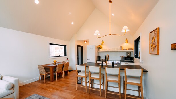 A modern kitchen with wooden flooring, a dining area with chairs, and a central island. - Maynard's Retreat | Hocking Hills, Modern, Hot Tub (Rockbridge)