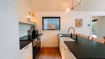 A compact kitchen with a black countertop, white cabinets, a window, and a sink.