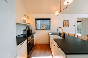 A compact kitchen with a black countertop, white cabinets, a window, and a sink.