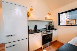 A kitchen with a refrigerator, stove, microwave, and wooden flooring.