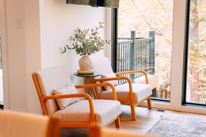 A room with two chairs, a small table, and a potted plant.