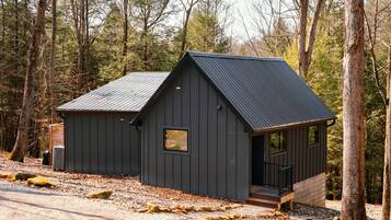 Een klein huisje met een metalen dak, een veranda en een raam.