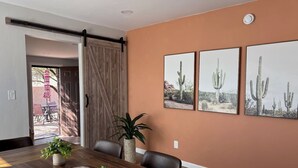 A dining area with a wooden table, chairs, and a sliding door leading to an outdoor patio. - Hot tub stargazing, pet friendly! Downtown & hiking nearby. (Tucson)