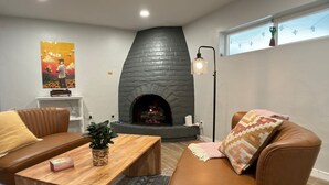 A cozy living room with a stone fireplace, leather sofa, wooden coffee table, and a potted plant. - Hot tub stargazing, pet friendly! Downtown & hiking nearby. (Tucson)