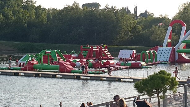 An outdoor water park with inflatable play structures and a dock.