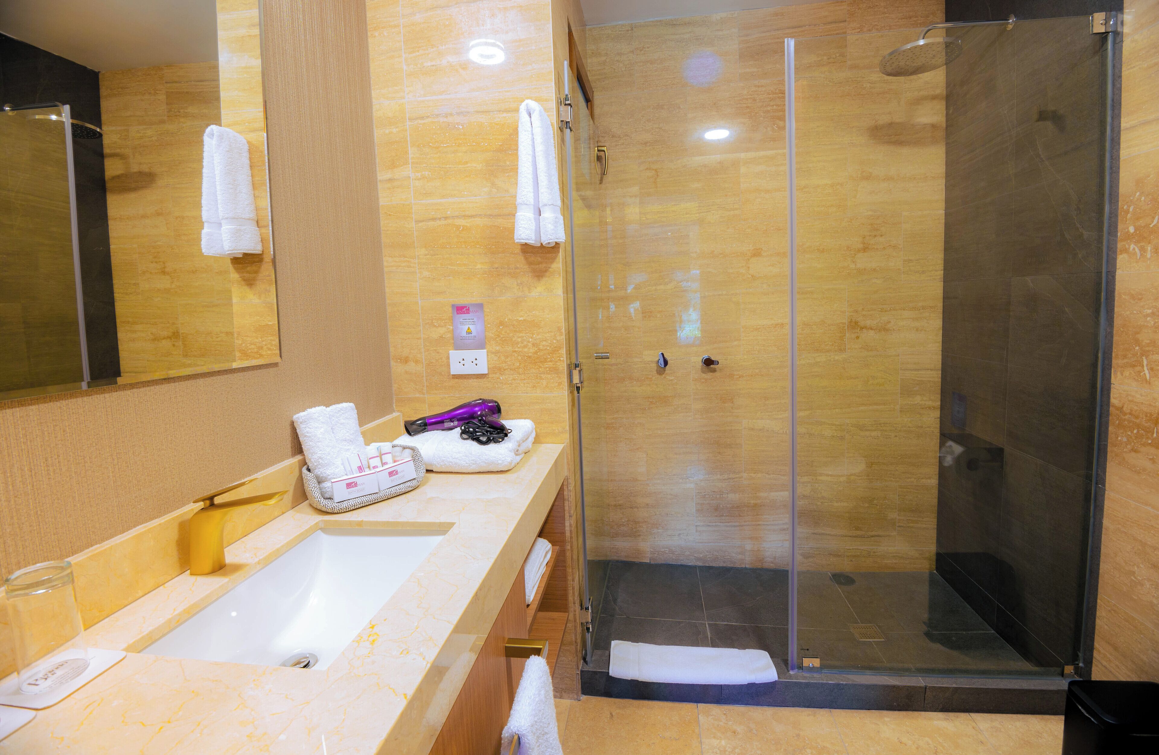 Une salle de bain moderne avec une douche à parois de verre, un lavabo en marbre et un grand miroir.