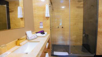 Une salle de bain moderne avec une douche à parois de verre, un lavabo en marbre et un grand miroir.