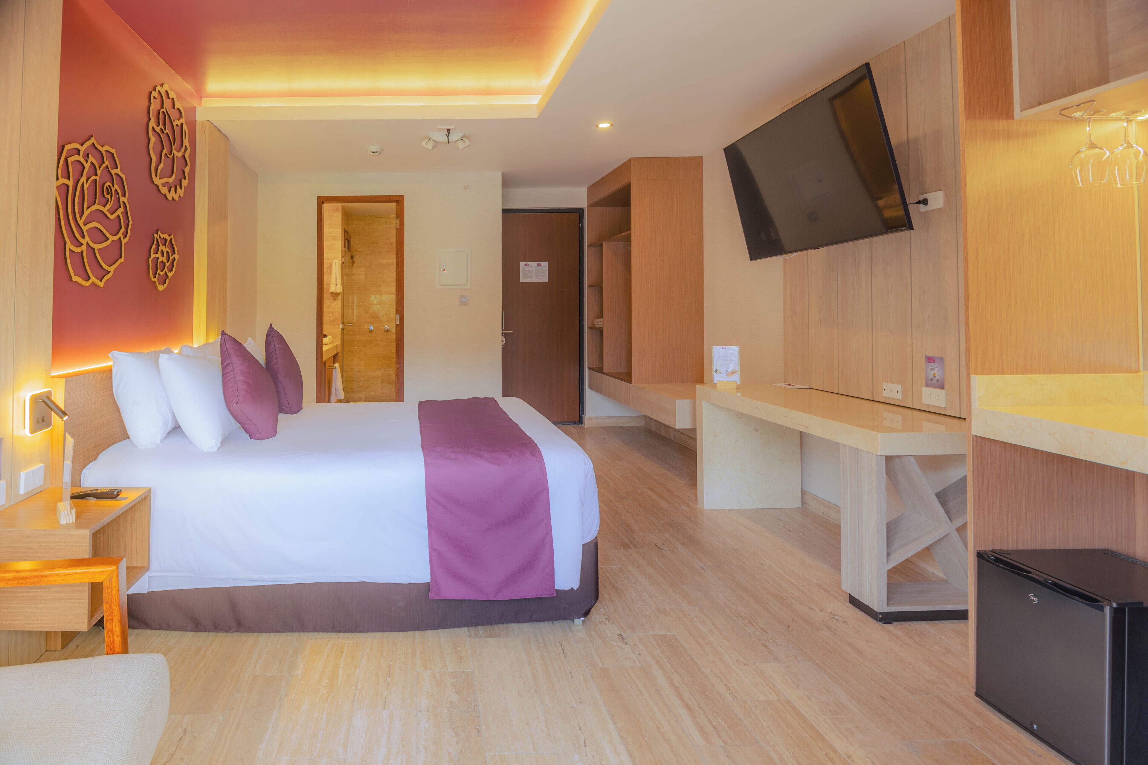 Een hotelkamer met een bed, nachtkastje, televisie en bureau.