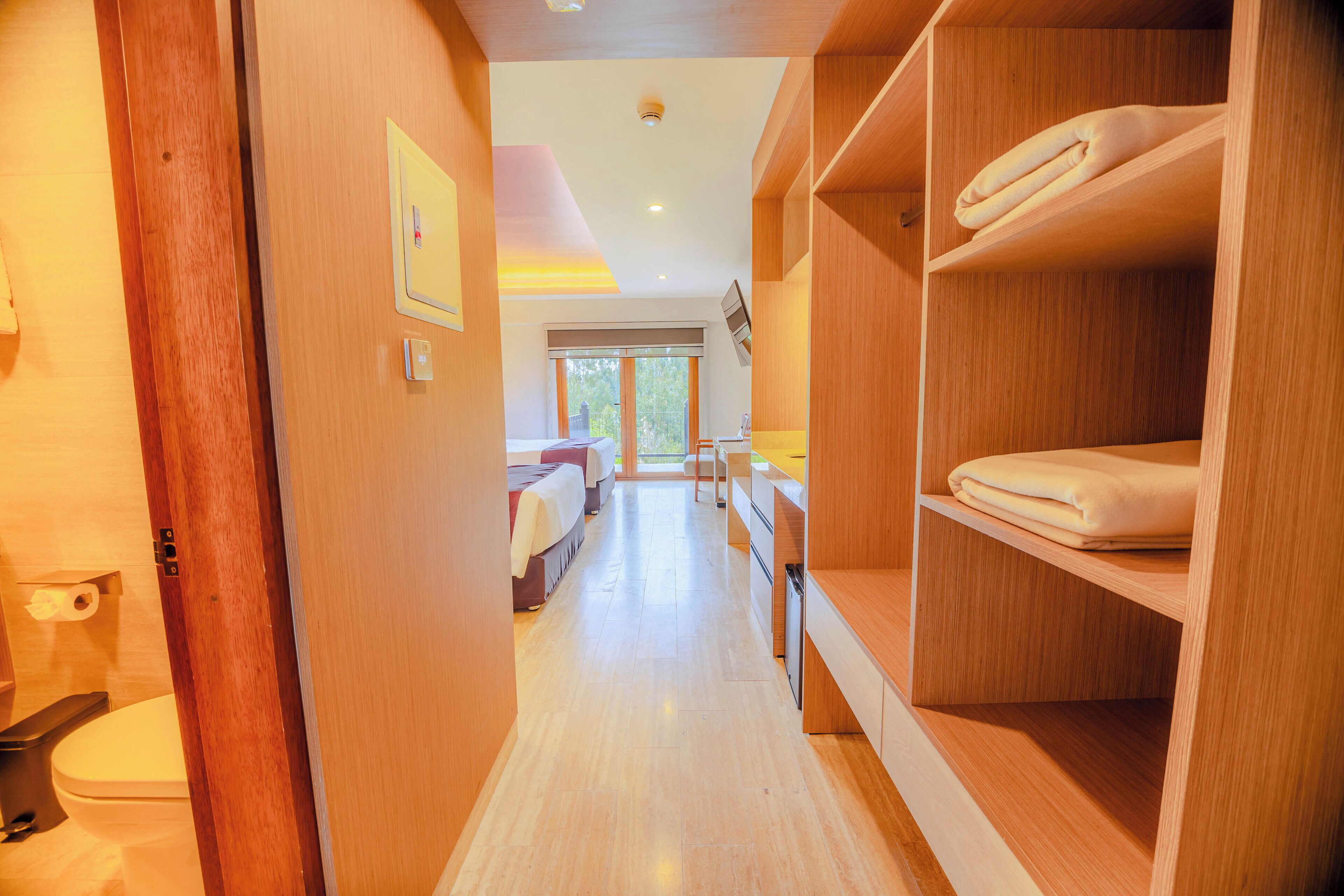 A hotel room with a wooden floor, a bed, a desk, and a wardrobe.