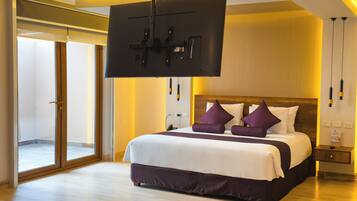 A modern hotel room with a large bed, a flat-screen TV mounted on the ceiling, and a sliding glass door leading to a balcony.