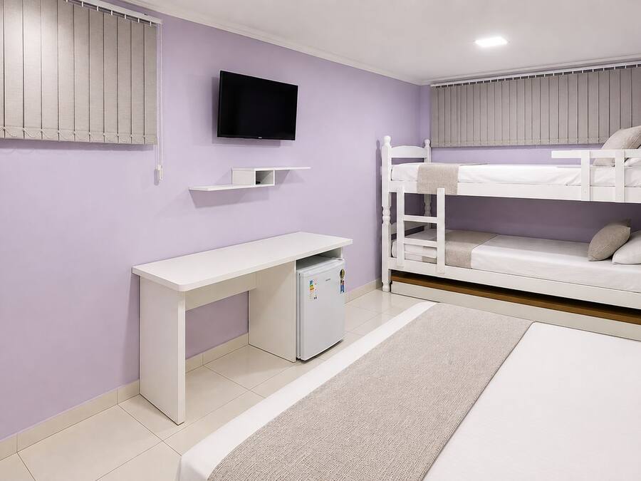 A bedroom with a bunk bed, a desk with a computer, and a TV mounted on the wall.
