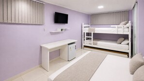 A bedroom with a bunk bed, a desk with a computer, and a TV mounted on the wall. - Alice Suites (Arraial do Cabo)