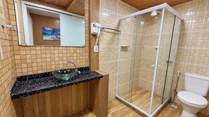A bathroom with a glass shower enclosure, a sink with a glass bowl, a toilet, and a wooden vanity. - Alice Suites (Arraial do Cabo)