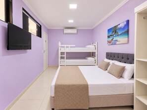 A room with a bunk bed, a flat bed with a patterned bedspread, a television mounted on the wall, and a painting of a beach scene. - Alice Suites (Arraial do Cabo)