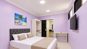 A bedroom with a bed, a TV, a painting, and a wardrobe. - Alice Suites (Arraial do Cabo)
