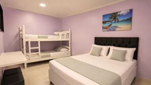 A bedroom with a bunk bed, a single bed, a desk, and a painting of a beach scene. - Alice Suites (Arraial do Cabo)