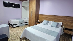 A bedroom with a large bed, a wardrobe, a bedside table, and a small desk. - Alice Suites (Arraial do Cabo)