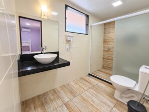 A modern bathroom with a white sink, a mirror, a toilet, and a shower area. - Alice Suites (Arraial do Cabo)