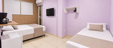 A hotel room with two beds, a TV, a coffee maker, and a small kitchenette.