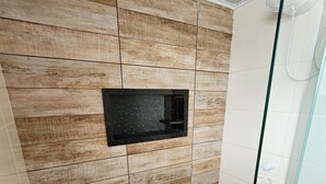 A modern bathroom with wooden panel walls, a built-in black sink, and a glass shower enclosure. - Alice Suites (Arraial do Cabo)