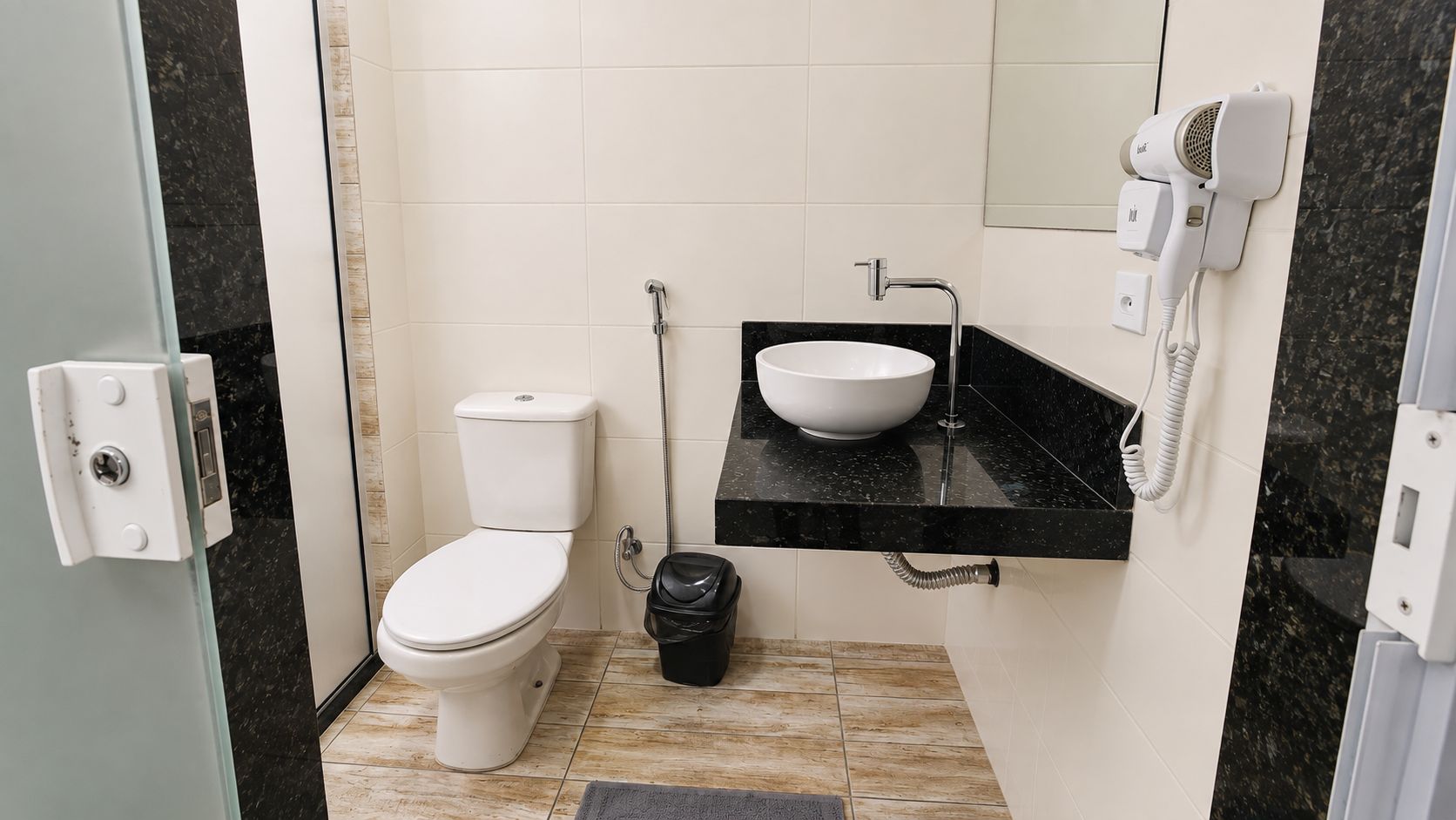 Casa de banho com sanita, lavatório e secador de cabelo.