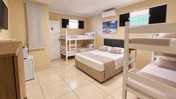 A bunk bed room with a desk, a door, and a window. - Alice Suites (Arraial do Cabo)