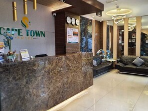A reception area with a marble counter, a sofa, and a chandelier. - CAPE TOWN HOTEL  (Dubai)