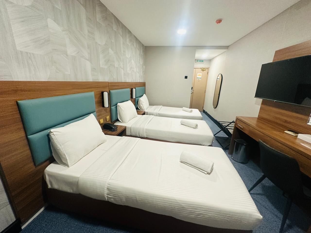 Une chambre d’hôtel avec deux lits, un bureau, une télévision et une poubelle.