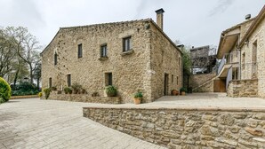 A stone building with multiple windows, a stone staircase, and potted plants. - Room 'Tramuntana' with Shared Pool, Wi-Fi and Air Conditioning (Girona)