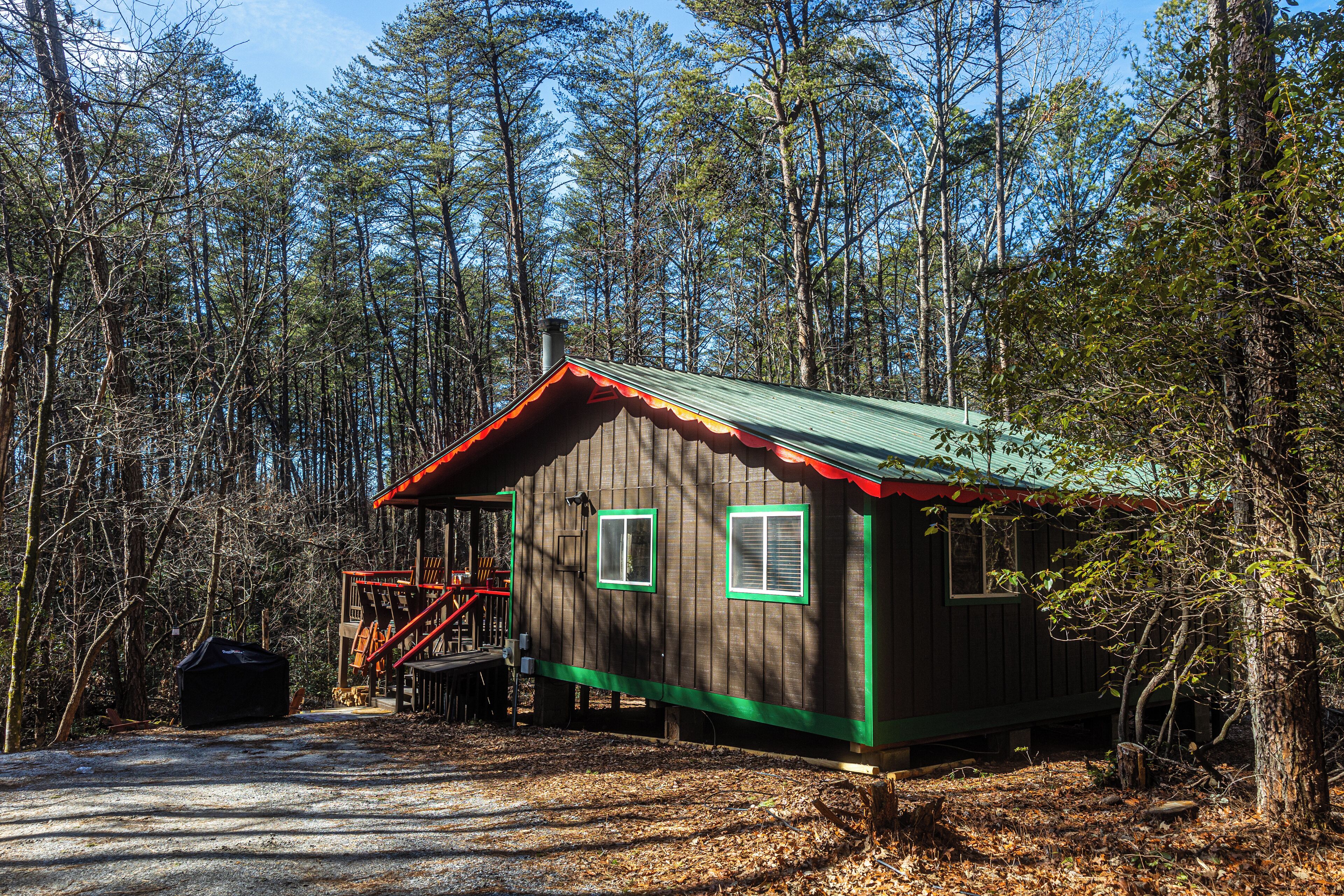 A cabin with a metal staircase leading to a deck, surrounded by a forest.